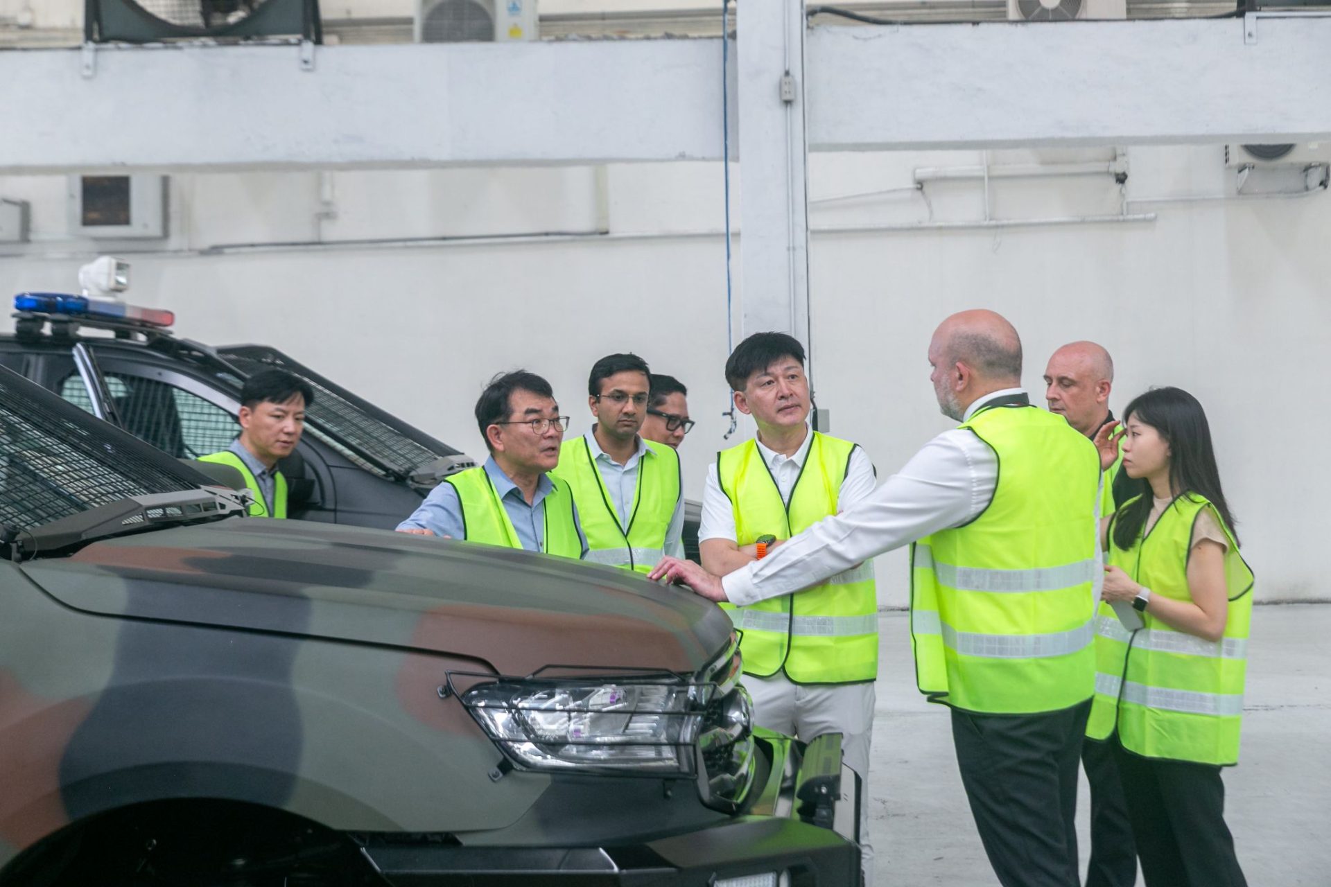 a group of people in reflective vests standing next to a car